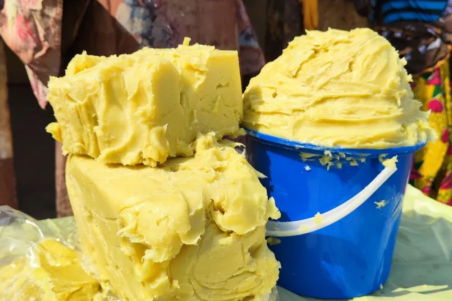 A tub of shea butter next to two big cubes of shea butter stacked on top of each other.